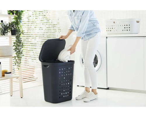 Panier à linge avec couvercle dans une salle de bain lumineuse avec machine à laver