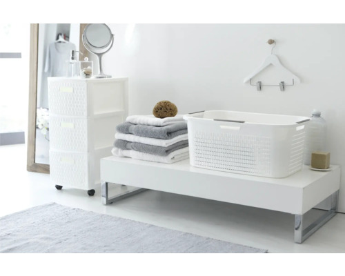 Badezimmerinterieur mit weissem Kunststoffwäschekorb, Handtüchern und Kommode