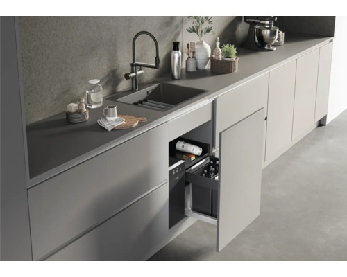 Cuisine avec évier, robinet et meuble bas ouvert avec des bouteilles