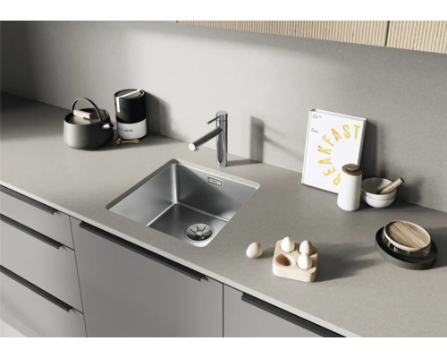 Évier de cuisine en acier inoxydable avec robinet sur un plan de travail.