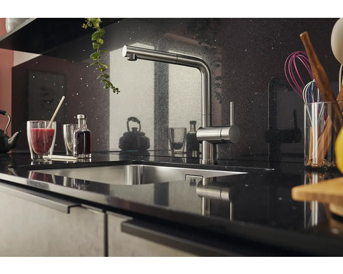 Scène de cuisine avec évier et robinet sur un plan de travail foncé.