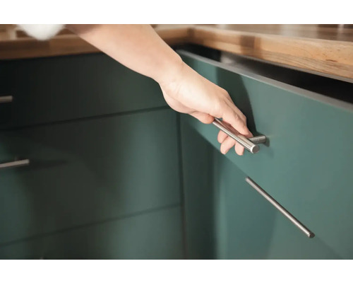 Gros plan d''une main ouvrant un placard de cuisine avec une poignée argentée.