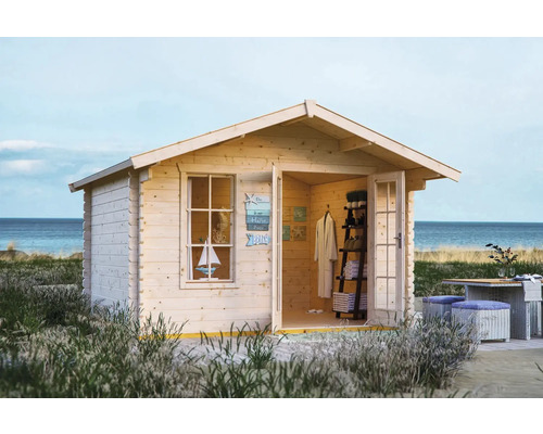 Abri en madriers SKAN HOLZ Langesund 1 avec plancher 380 x 350 cm naturel Maison de jardin en bois avec porte ouverte, fenêtre et décoration maritime installée sur la plage.