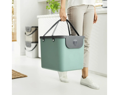 Frau trägt einen türkisfarbenen Eimer mit Griffen zum Abfalltrennen