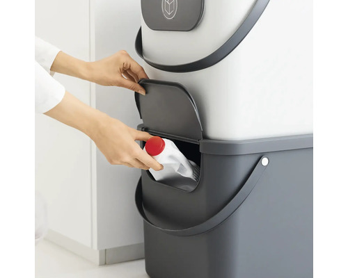 Femme jette une bouteille vide dans une poubelle de recyclage grise