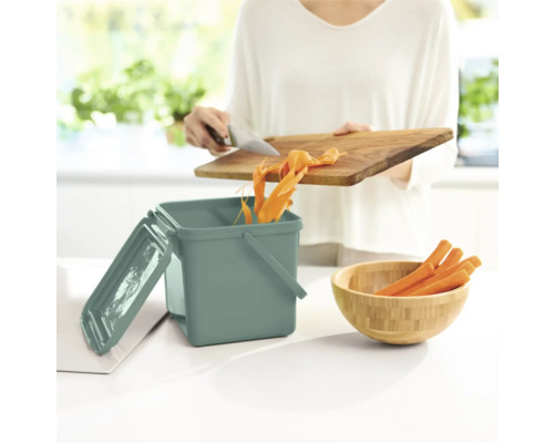 Scène de cuisine avec poubelle à compost, planche à découper et carottes