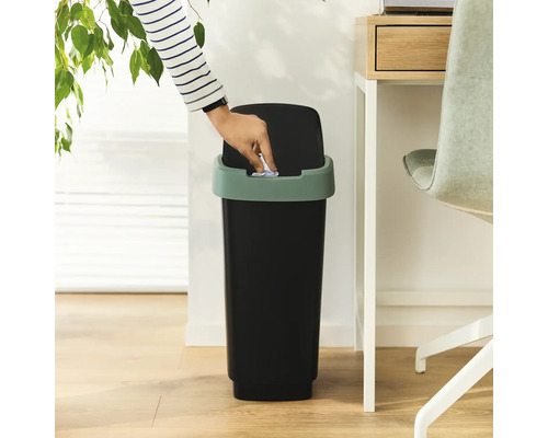 Person wirft Papier in einen Abfalleimer mit Schwingdeckel