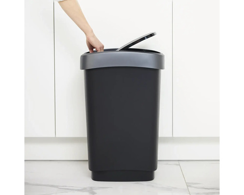 Poubelle avec couvercle dans une pièce lumineuse avec une main ouvrant le couvercle