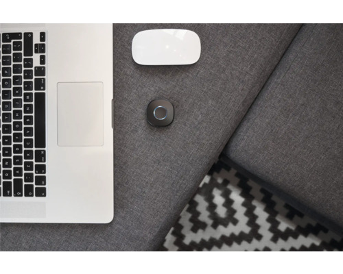 Laptop, Computermaus und Smart Home Gerät auf einem grauen Sofa