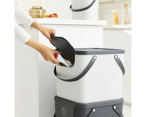 Person wirft Gegenstand in einen Eimer mit Deckel