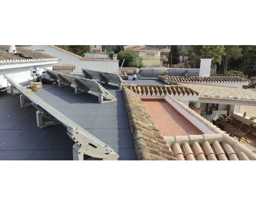 Installation de panneaux solaires sur un toit avec des tuiles et une étanchéité bitumineuse.