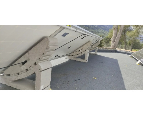 Panneaux solaires surélevés sur un toit avec supports en béton.