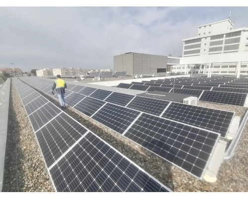 Photographie de panneaux solaires sur un toit avec une personne portant un gilet de sécurité