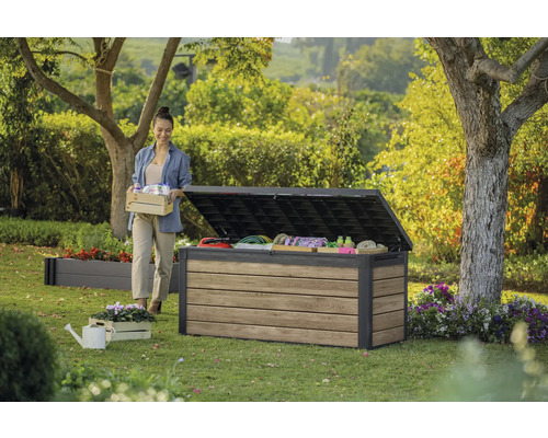 Coffre de jardin ouvert dans le jardin avec femme, jardinière et arrosoir