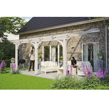 Terrasse avec pergola en bois et coin salon sur une surface pavée à côté d''une maison.