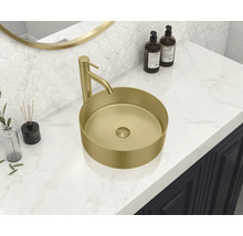 Un lavabo à poser de couleur or avec robinetterie se trouve sur un lavabo