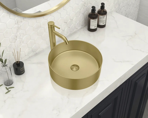 Un lavabo à poser de couleur or avec robinetterie se trouve sur un lavabo