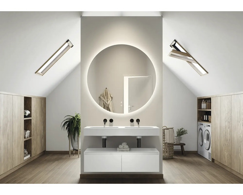 Salle de bains lumineuse dans les combles avec miroir rond, meuble sous-vasque, fenêtres de toit et placards intégrés.