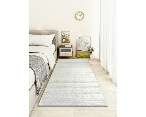 Chambre avec lit, table de chevet, décoration et tapis clair à motifs.