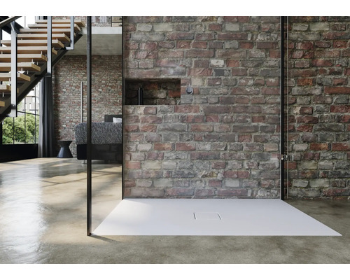 Douche à l''italienne avec receveur devant un mur en briques dans une salle de bains moderne.