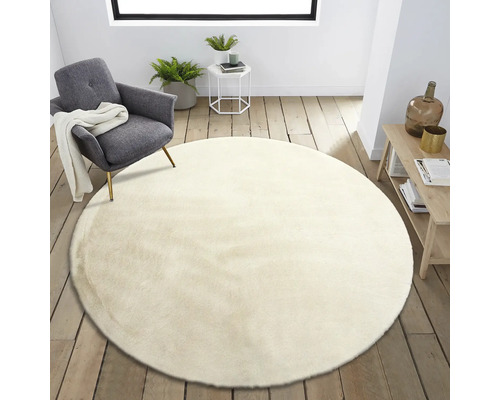 Tapis rond beige dans le salon à côté d''un fauteuil et d''une table