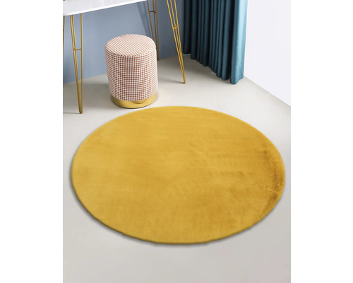Gelber runder Teppich im Raum mit Tisch und Hocker