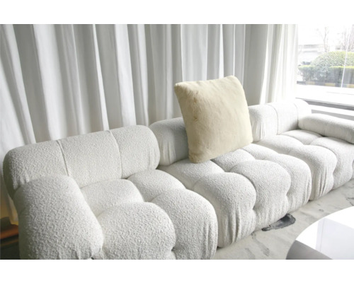 Canapé modulaire avec coussin devant une fenêtre avec des rideaux