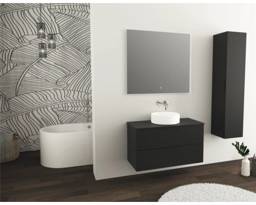 Salle de bain moderne avec meuble-lavabo, miroir, armoire haute et baignoire îlot devant un mur à motif de feuilles