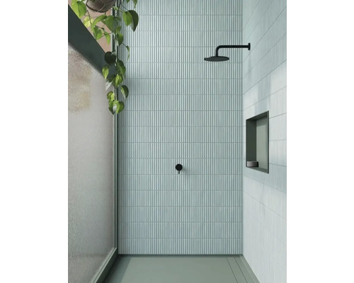 Salle de douche moderne avec des carreaux verticaux étroits, une pomme de douche et une étagère intégrée