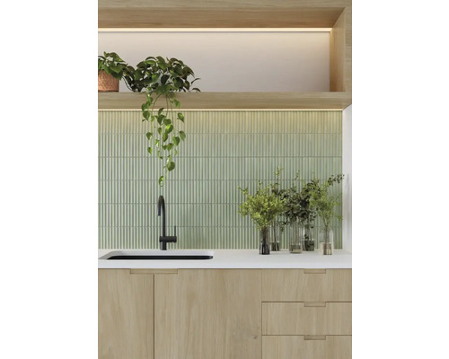 Scène de cuisine avec évier, robinet, plan de travail, crédence carrelée verte et plantes d''intérieur