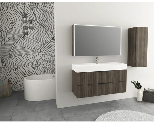 Salle de bains avec meuble-lavabo, armoire de toilette éclairée, armoire suspendue et baignoire devant un mur à motif de feuilles