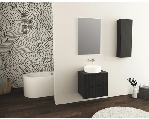 Salle de bain avec lavabo, miroir, armoire suspendue et baignoire autoportante devant un mur à motif de feuilles