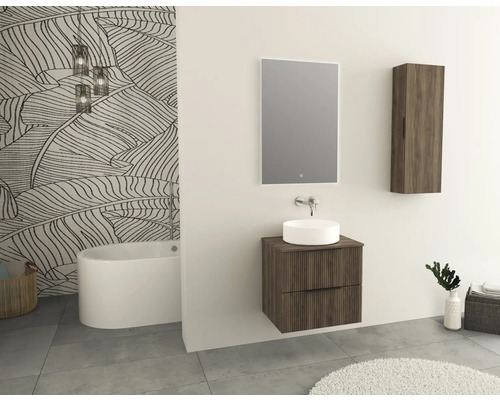 Salle de bains moderne avec lavabo, miroir, armoire suspendue et baignoire îlot devant un mur avec papier peint à motifs de feuilles