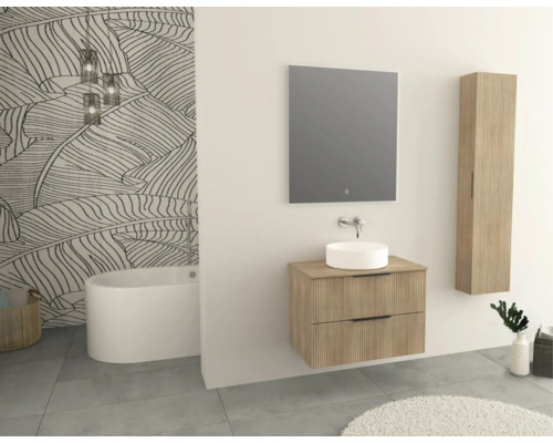 Salle de bains avec meuble-lavabo, miroir, armoire haute et baignoire devant un papier peint à motifs de feuilles