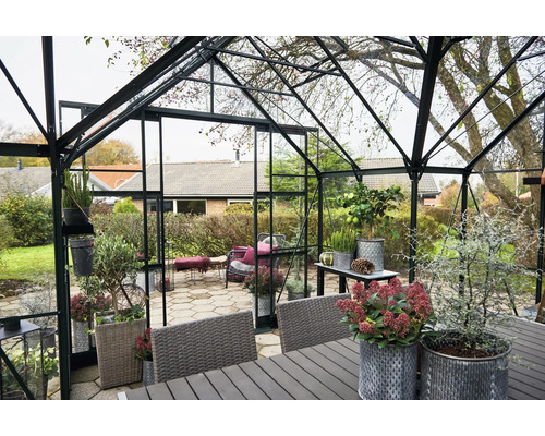Serre avec plantes et mobilier de jardin dans un jardin.
