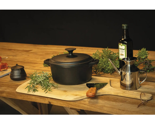 Arrangement mit einem Topf, einem Ölspender und Gewürzen auf einem Holztisch