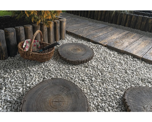 Gartenszene mit Kies, Baumstamm-Trittsteinen, Holzzaun und Gartengeräten