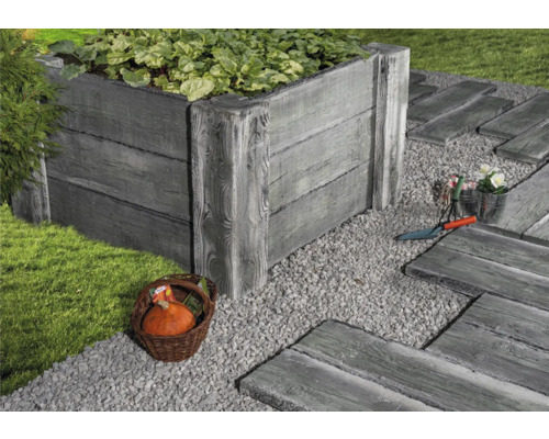 Gartenszene mit Hochbeet, Kiesweg und Dekorationen.