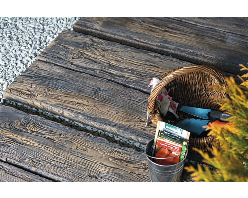 Chemin de jardin en dalles de béton aspect bois, avec outils de jardin et sachets de graines