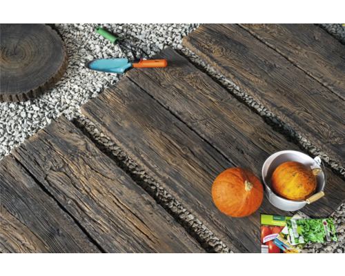 Chemin de jardin avec des pas japonais aspect bois, gravier, potirons et outils de jardin.