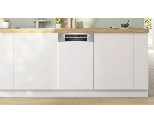 Lave-vaisselle intégré dans une cuisine moderne avec des armoires blanches et un plan de travail en bois.