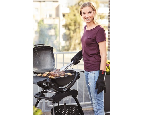 Frau grilliert mit Grillzange Fleisch auf einem Holzkohlegrill im Freien