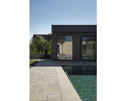 Aussenansicht eines modernen Schwimmbads mit Travertinplatten und Gebäude