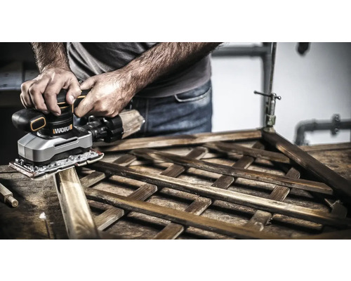 Un homme ponce un cadre en bois avec une ponceuse Worx.