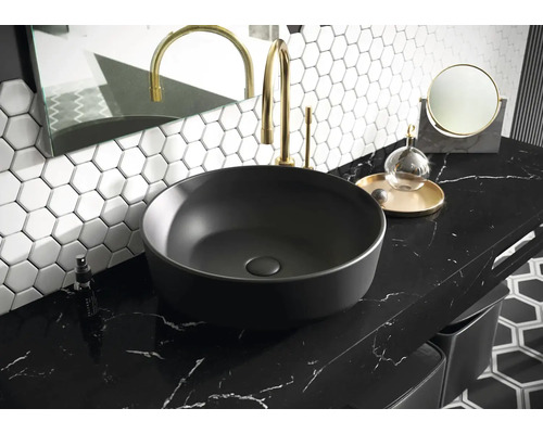 Lavabo sur plan de travail dans salle de bains avec robinetterie, miroir et carrelage hexagonal