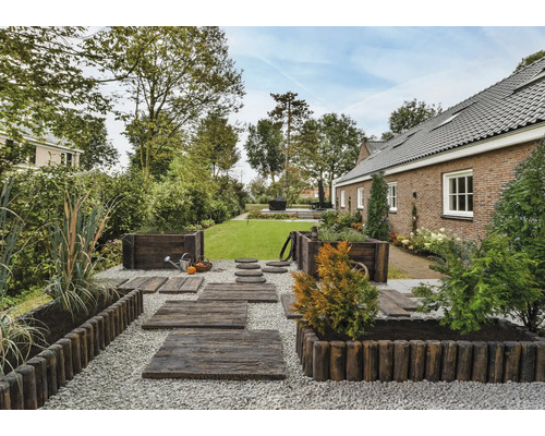 Jardin aménagé avec chemin en bois, parterres et pelouse devant une maison d''habitation.