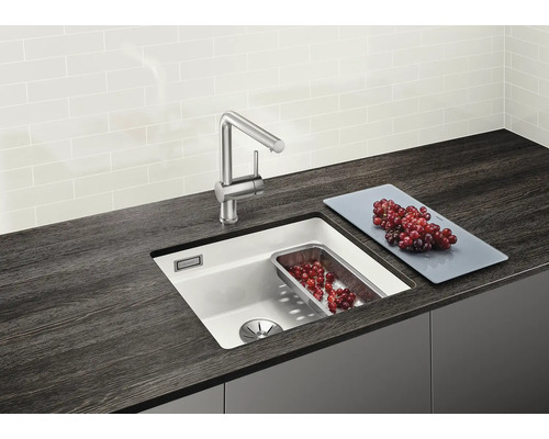 Évier de cuisine avec robinet, planche à découper et insert en acier inoxydable sur un plan de travail