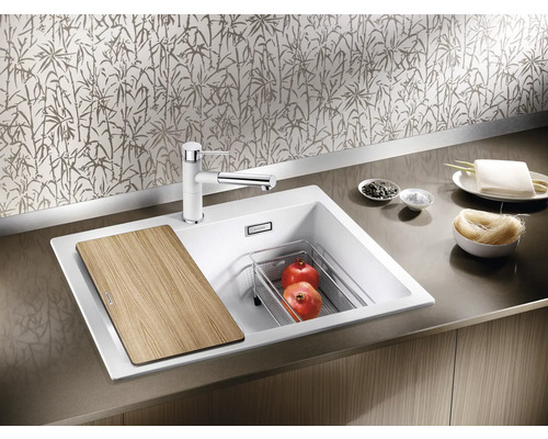 Küchenspüle mit Schneidebrett, Abtropfschale, Armatur und Lebensmitteln.
