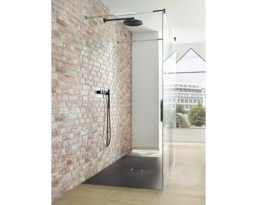 Douche à l''italienne avec cabine de douche vitrée, pomme de douche et robinet devant un mur de briques