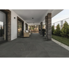 Terrasse couverte avec carrelage de sol foncé et piliers en briques.